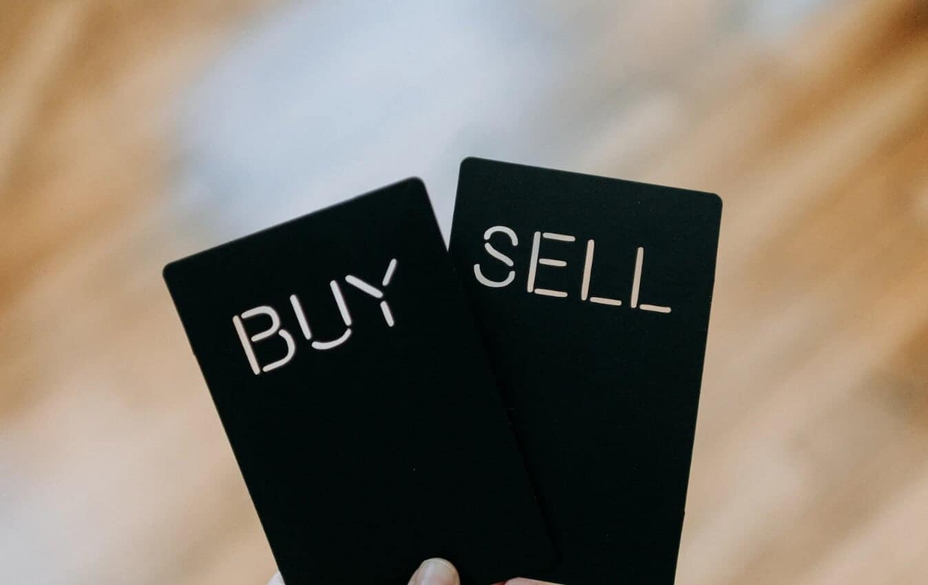a hand holding a buy and sell card