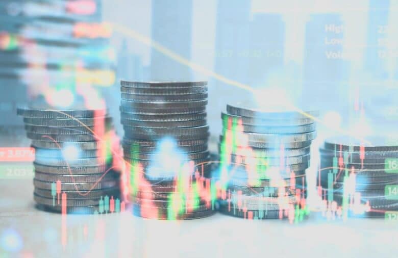 stacked coins behind virtual forex chart that is green and red