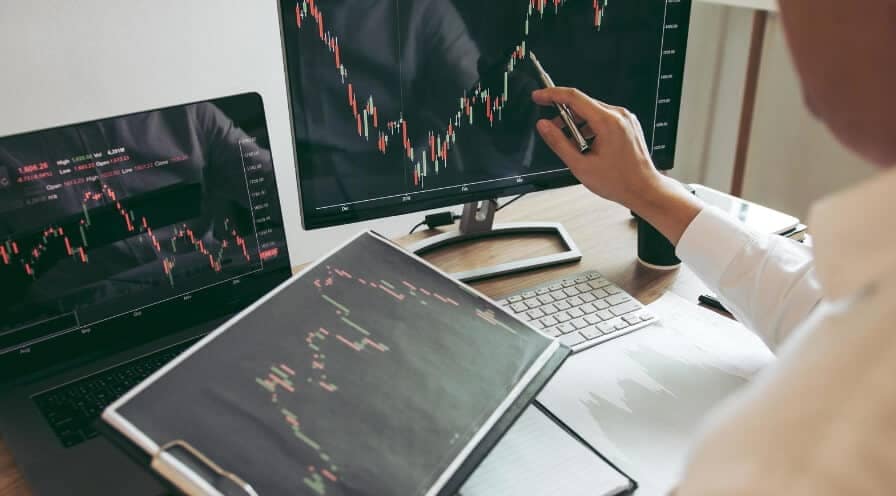 person holding forex chart and watching computer